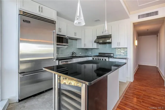a kitchen with kitchen island granite countertop a sink stainless steel appliances and cabinets