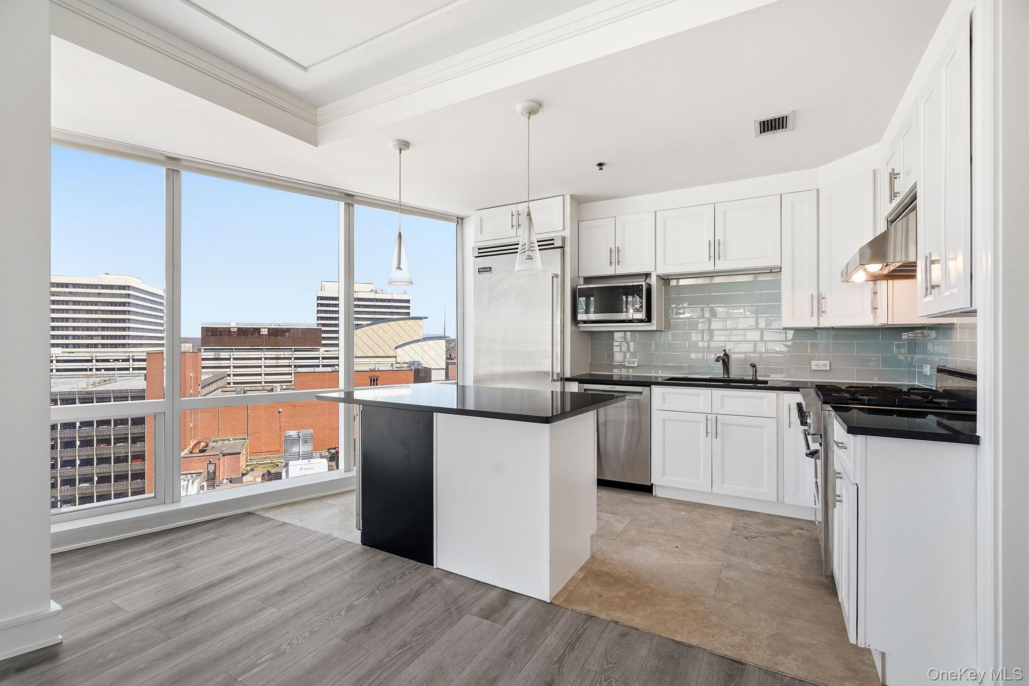 1 Renaissance Square, Unit 11G White Plains, NY 10601 - Photo 10 of 28 a kitchen with stainless steel appliances a stove a sink dishwasher a refrigerator and white cabinets with wooden floor