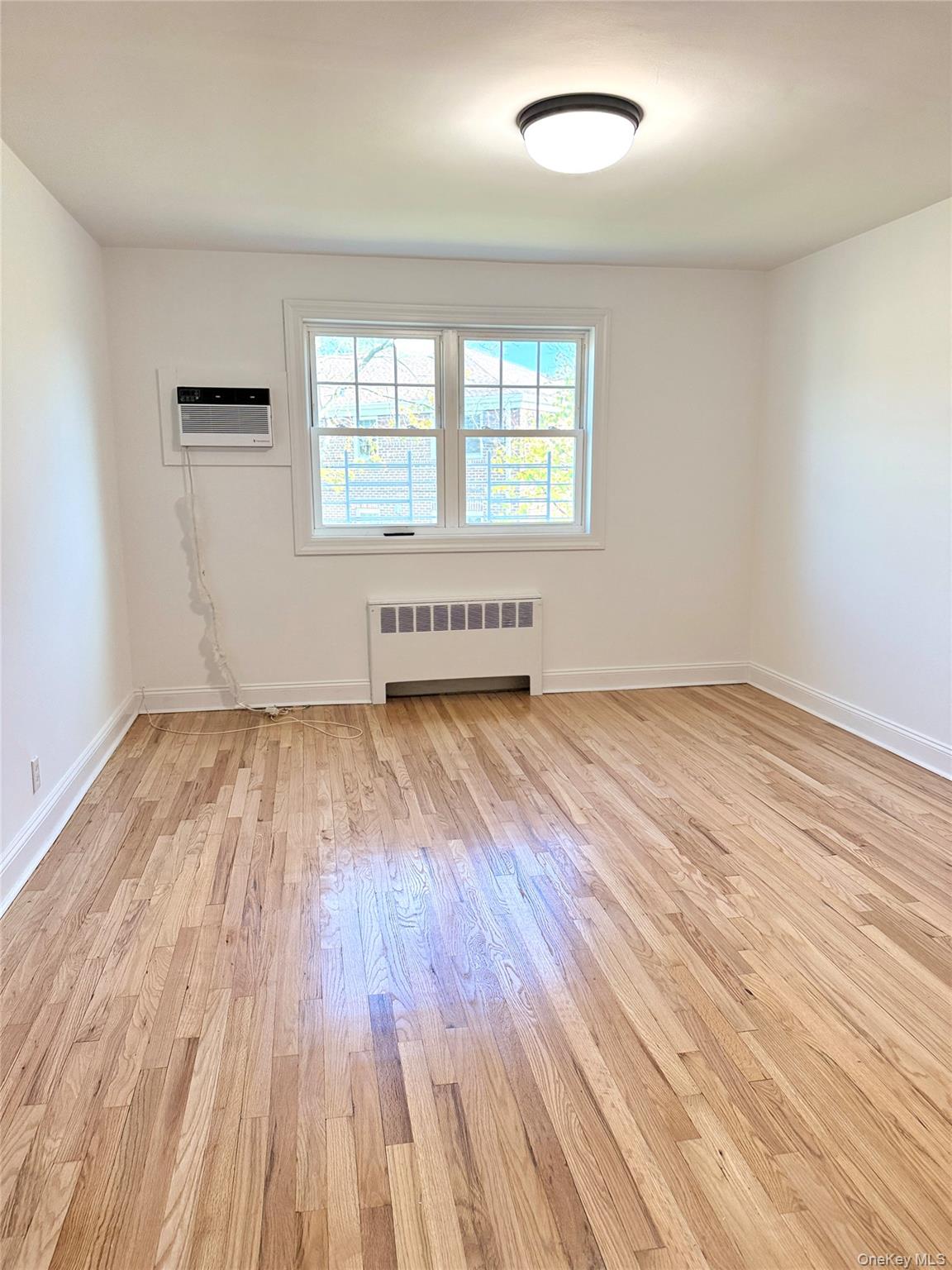 224-06 Springfield Boulevard, Unit 7815B Queens, NY 11364 - Photo 15 of 18 an empty room with wooden floor and windows
