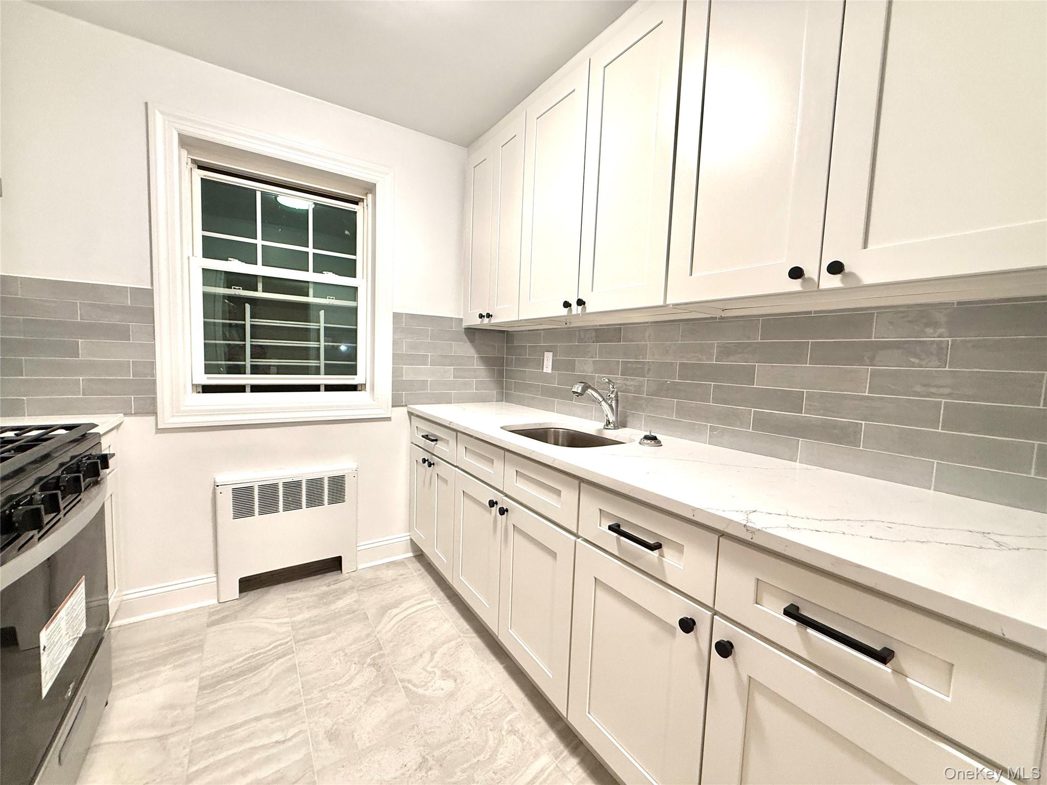 224-06 Springfield Boulevard, Unit 7815B Queens, NY 11364 - Photo 8 of 18 a kitchen with granite countertop a sink a stove and cabinets