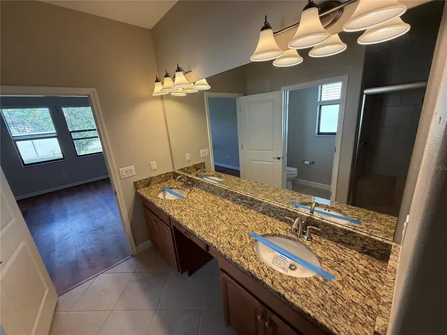 a bathroom with a granite countertop sink a light fixture and a mirror