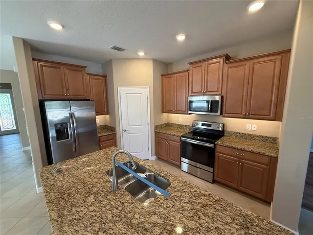 a kitchen with granite countertop a refrigerator stove and sink