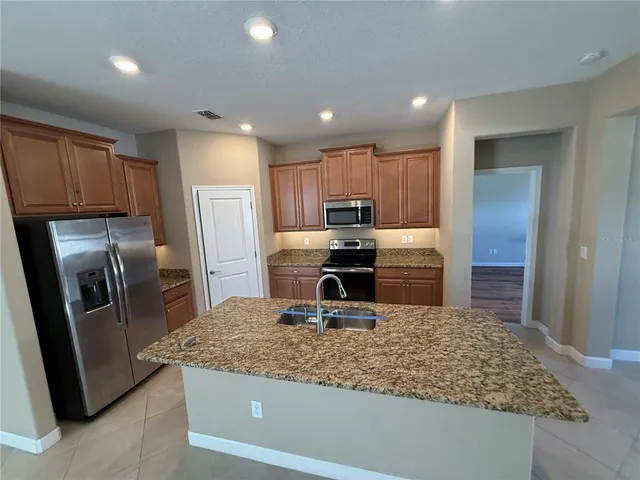 a kitchen with kitchen island a counter top space a sink and stainless steel appliances