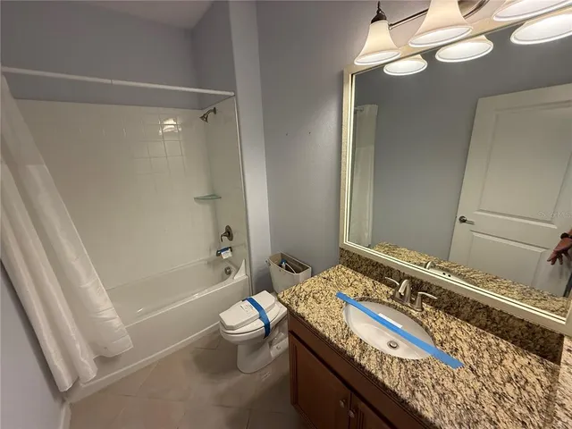 a bathroom with a granite countertop bathtub sink vanity mirror and toilet