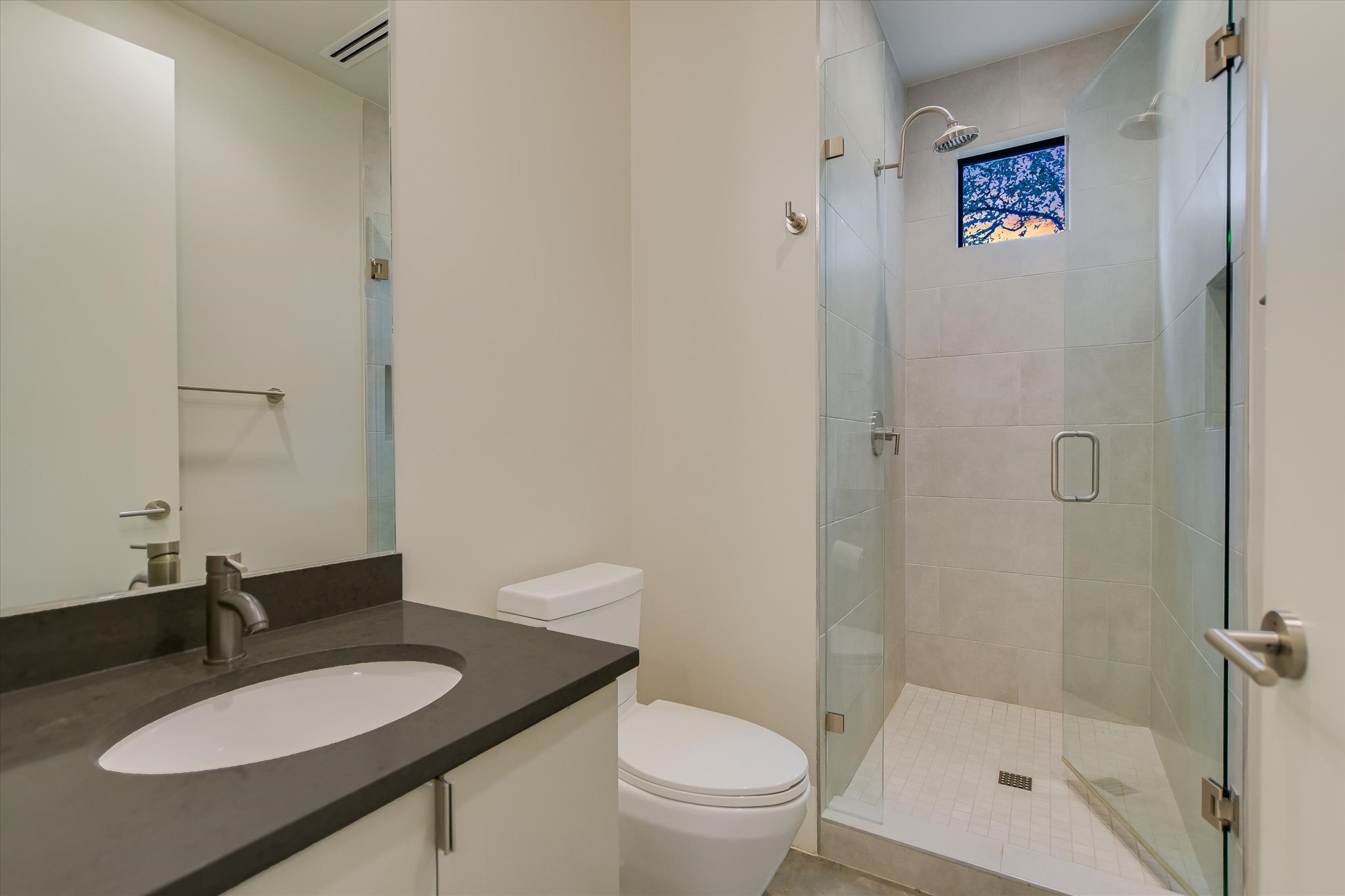 1325 Bonham Terrace, Unit A Austin, TX 78704 - Photo 20 of 25 a bathroom with a granite countertop sink toilet a mirror and shower