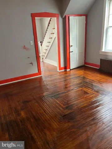 a view of an empty room with window and wooden floor