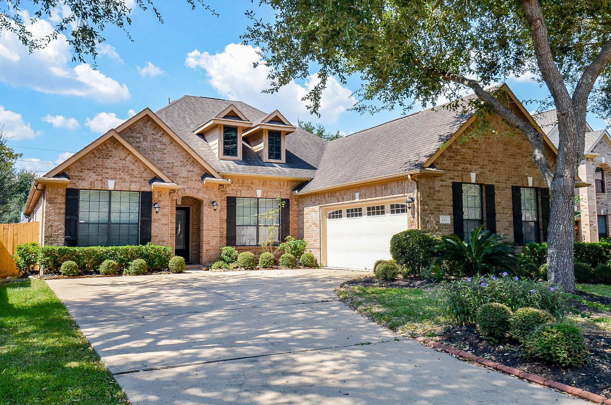  By day, the home’s classic architecture takes center stage, its wide driveway shaded by a mature tree as it arches gracefully toward the attached garage.