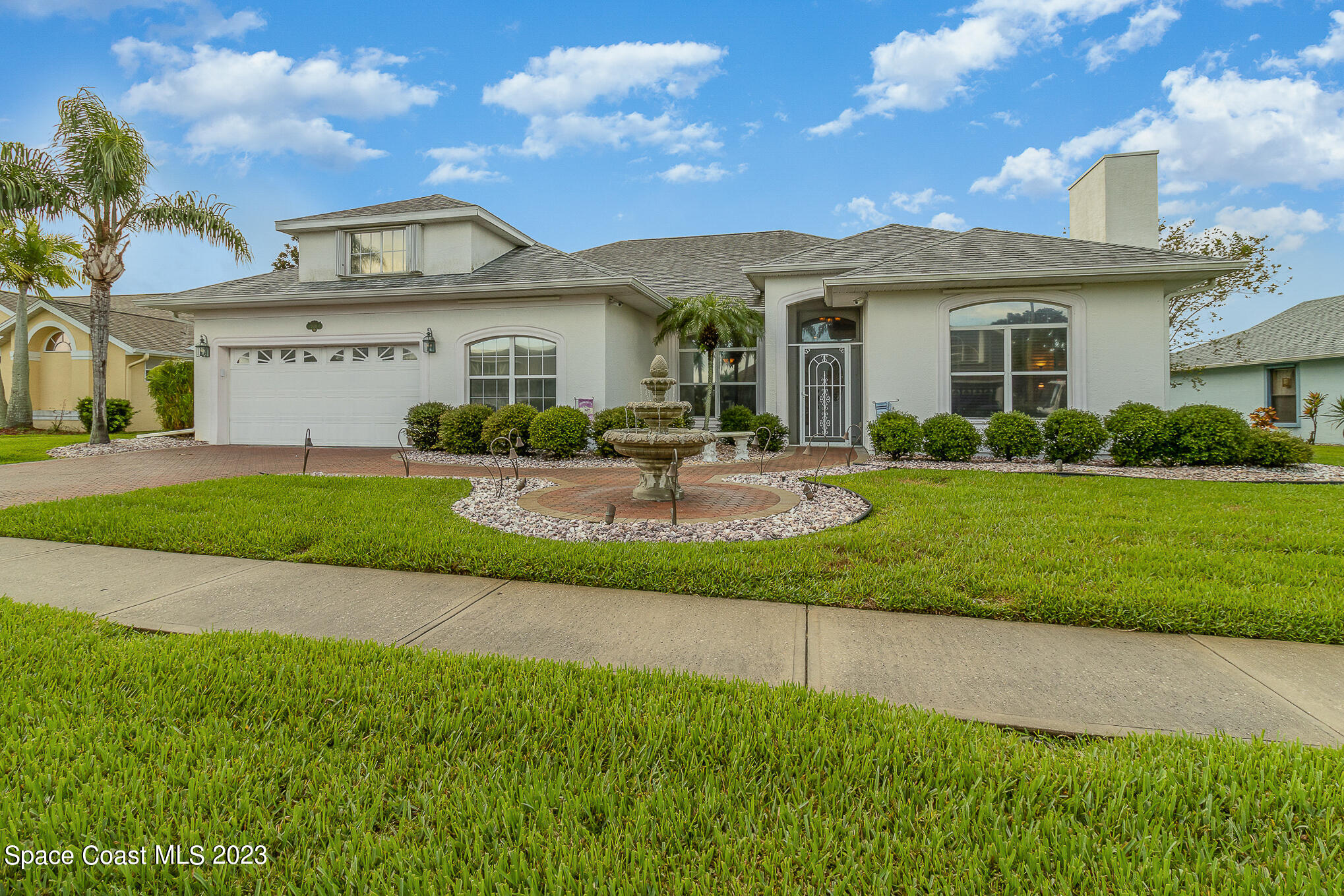 a front view of a house with a yard and potted plants