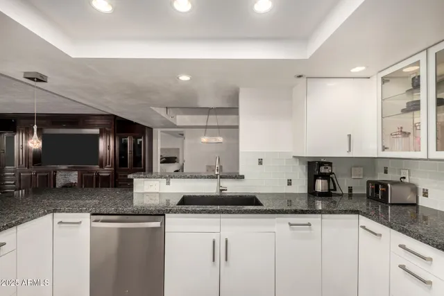 a kitchen with granite countertop a sink a stove cabinets and counter space