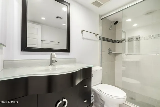 a bathroom with a sink a toilet a mirror and shower