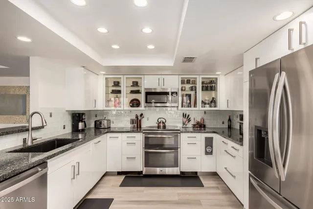 a kitchen with stainless steel appliances granite countertop a sink stove and refrigerator