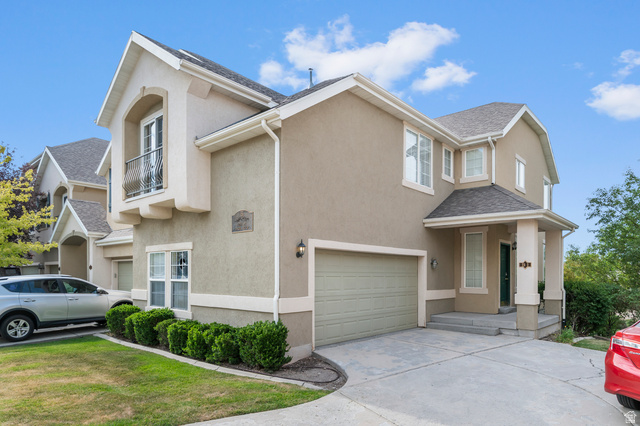 3053 Sage Loop, Unit B1 Lehi, UT 84043 - Photo 2 of 25 Stucco exterior with a peaked roofline, front-facing garage, covered entryway, and a Juliet balcony
