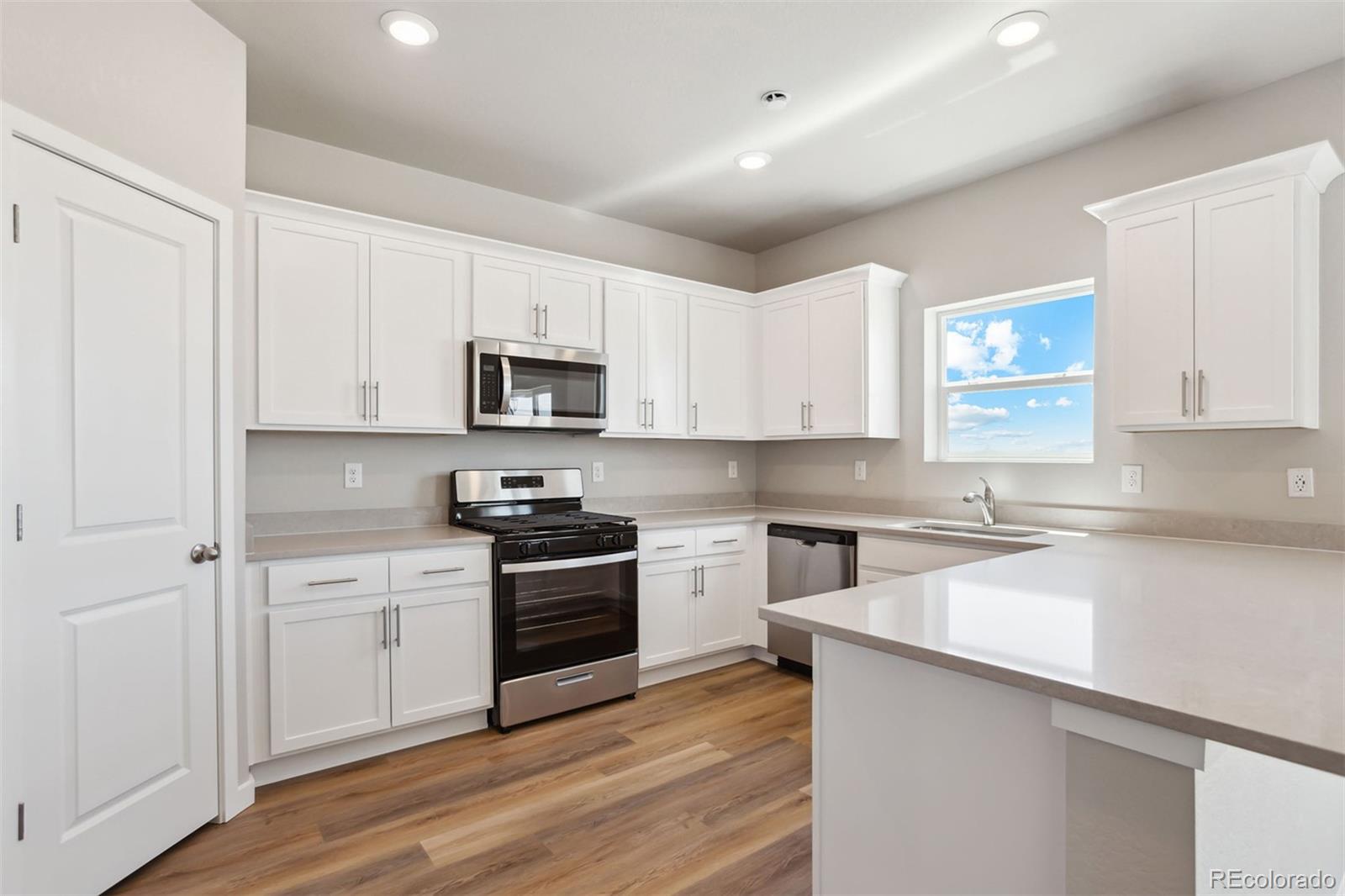 48165 Shetland Drive Bennett, CO 80102 - Photo 7 of 21 a kitchen with granite countertop white cabinets and stainless steel appliances
