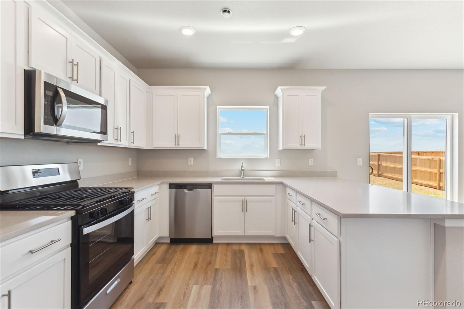 48165 Shetland Drive Bennett, CO 80102 - Photo 8 of 21 a kitchen with stainless steel appliances granite countertop a stove a sink and a microwave