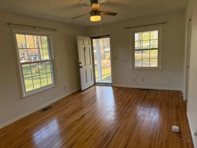 a view of an empty room with wooden floor and a window