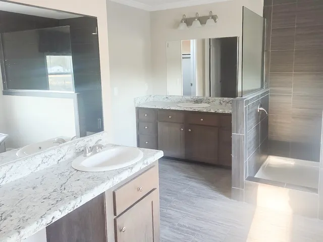 a bathroom with a granite countertop sink a mirror and a shower