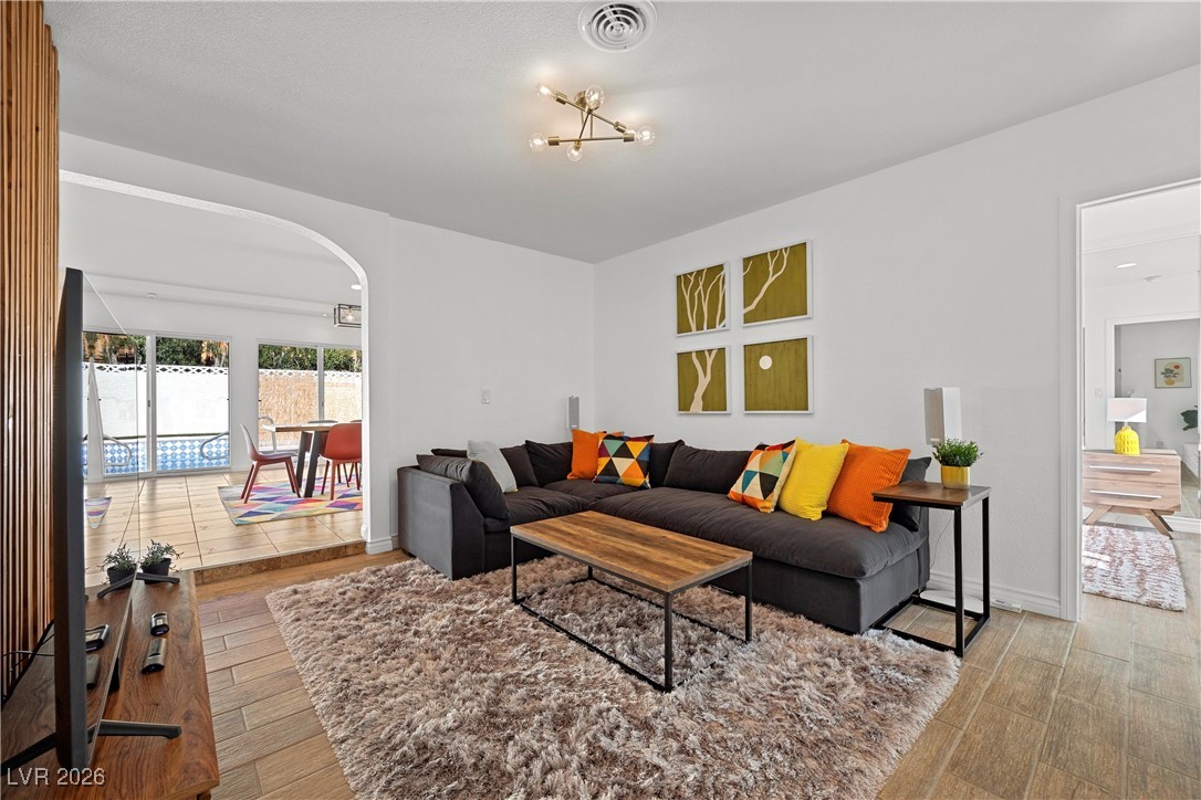 1554 Raindance Way Las Vegas, NV 89169 - Photo 3 of 25 Living room featuring baseboards, visible vents, arched walkways, and wood finished floors