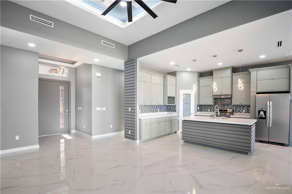 1402 Tee Box Drive Weslaco, TX 78596 - Photo 5 of 20 a large white kitchen with kitchen island a sink stainless steel appliances and cabinets