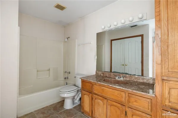 a bathroom with a granite countertop toilet a sink and a mirror