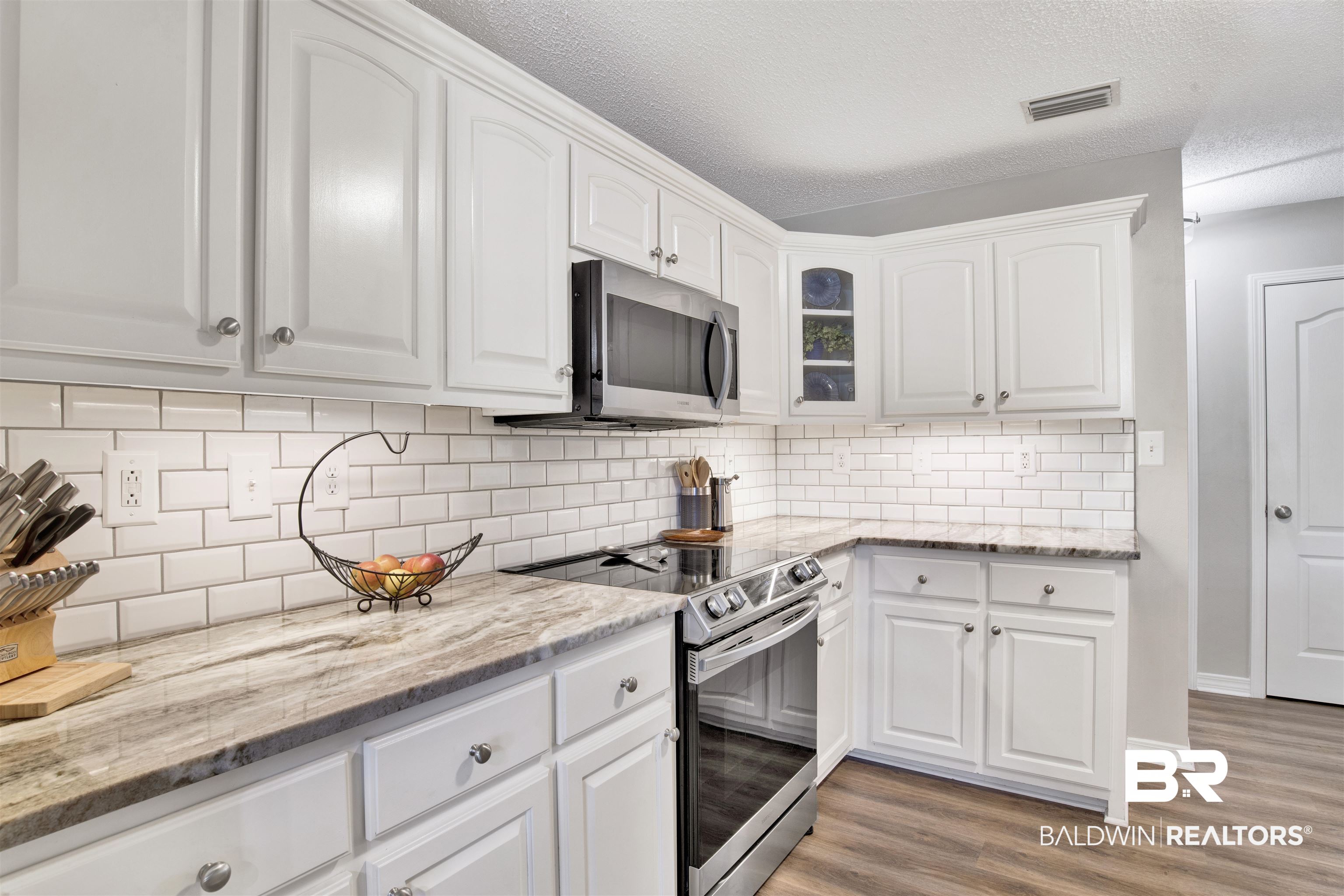 17483 East View Loop Foley, AL 36535 - Photo 18 of 30 Kitchen featuring a textured ceiling, stainless steel appliances, light wood-type flooring, and white cabinetry