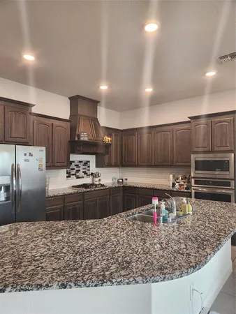 a kitchen with stainless steel appliances granite countertop a stove top oven a sink refrigerator and cabinets