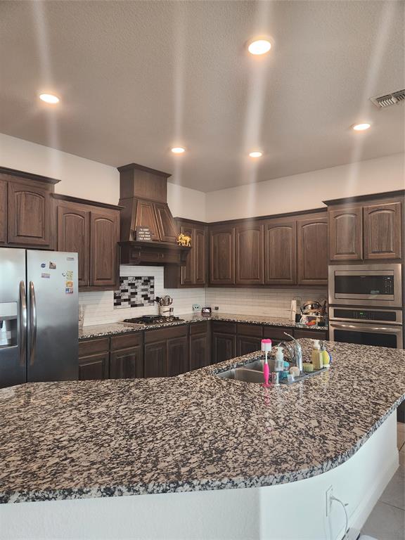10929 Big Spring Trail McKinney, TX 75071 - Photo 5 of 13 a kitchen with stainless steel appliances granite countertop a stove top oven a sink refrigerator and cabinets