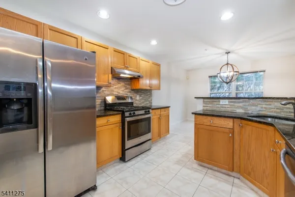 a kitchen with stainless steel appliances granite countertop a refrigerator a stove and a sink