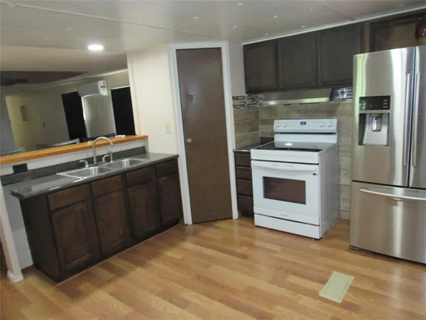 a kitchen with stainless steel appliances granite countertop a refrigerator a stove a sink and a oven