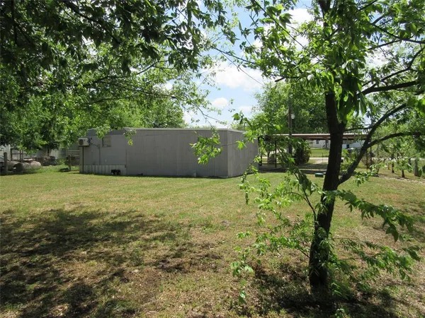 a view of a green field with trees in the background