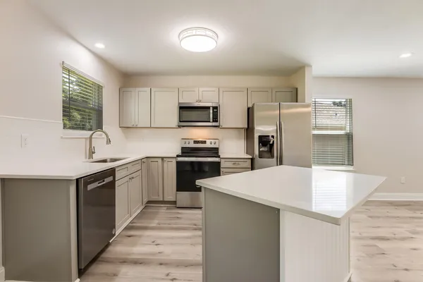 a kitchen with a refrigerator a stove top oven a sink and cabinets