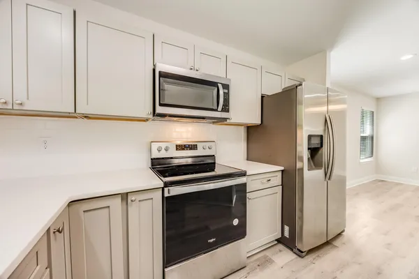 a kitchen with stainless steel appliances white cabinets white stove a microwave and a refrigerator