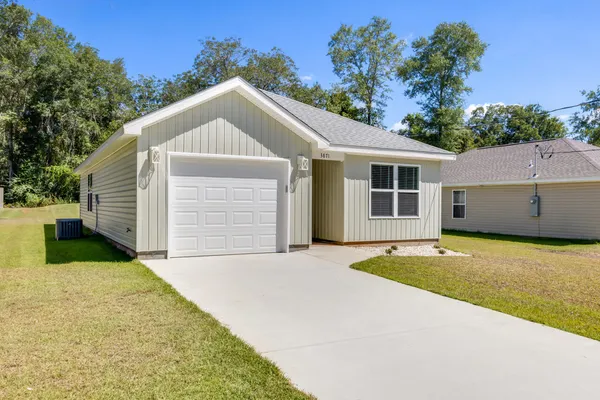 a view of a house with backyard and trees in the background