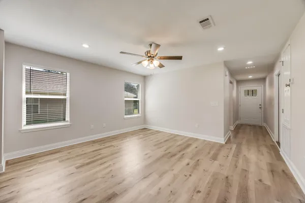 an empty room with wooden floor and windows