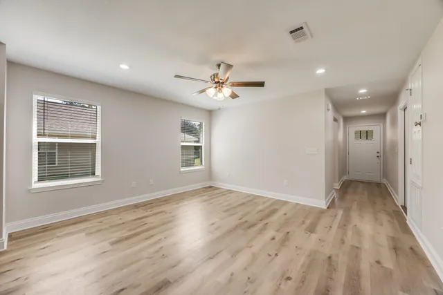 an empty room with wooden floor and windows