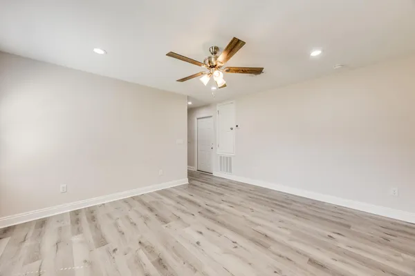 an empty room with wooden floor and a ceiling fan