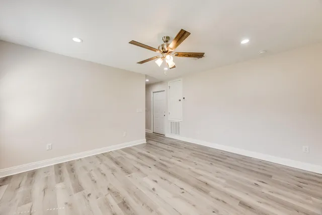 an empty room with wooden floor and a ceiling fan