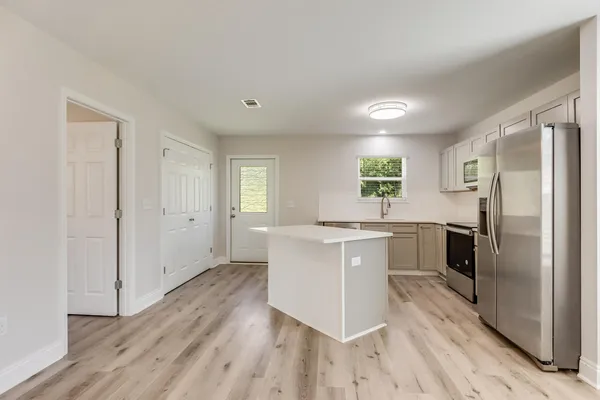 a kitchen with a refrigerator and white cabinets