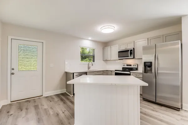 a kitchen with kitchen island a counter top space stainless steel appliances and a window