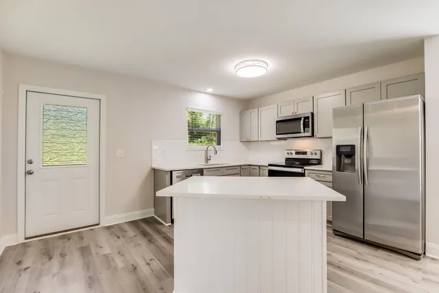 a kitchen with kitchen island a counter top space stainless steel appliances and a window
