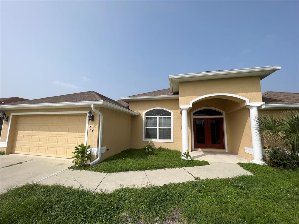 99 Flanders Street Port Charlotte, FL 33954 - Photo 2 of 29 a front view of a house with a yard and garage