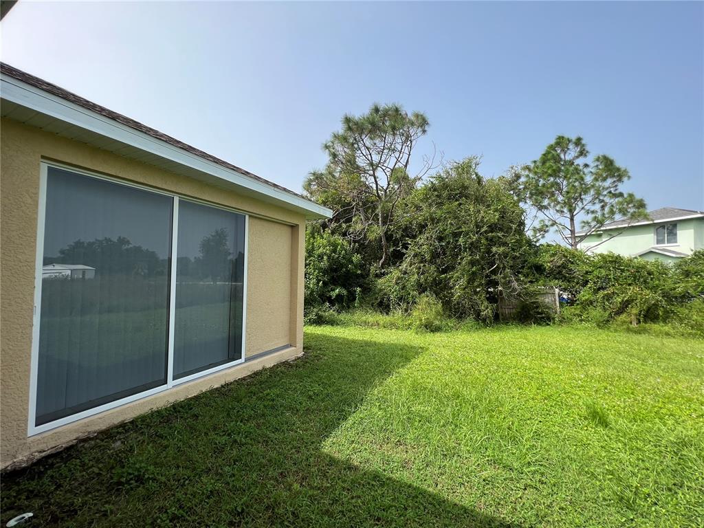 99 Flanders Street Port Charlotte, FL 33954 - Photo 29 of 29 a view of a backyard with potted plants and a large tree