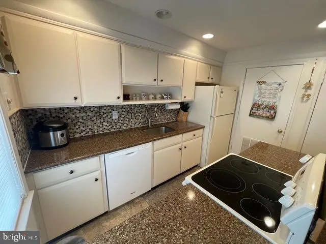 a kitchen with white cabinets and white appliances