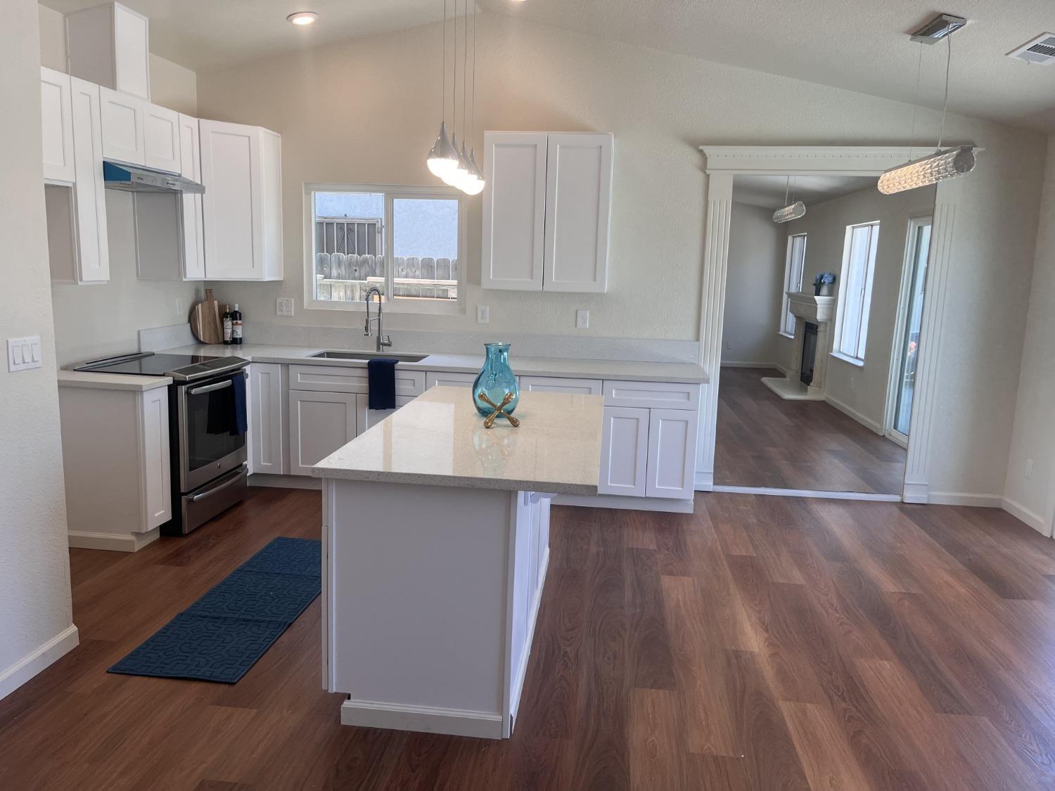 605 El Monte Street Madera, CA 93637 - Photo 2 of 17 a kitchen with a sink wooden floor and stainless steel appliances