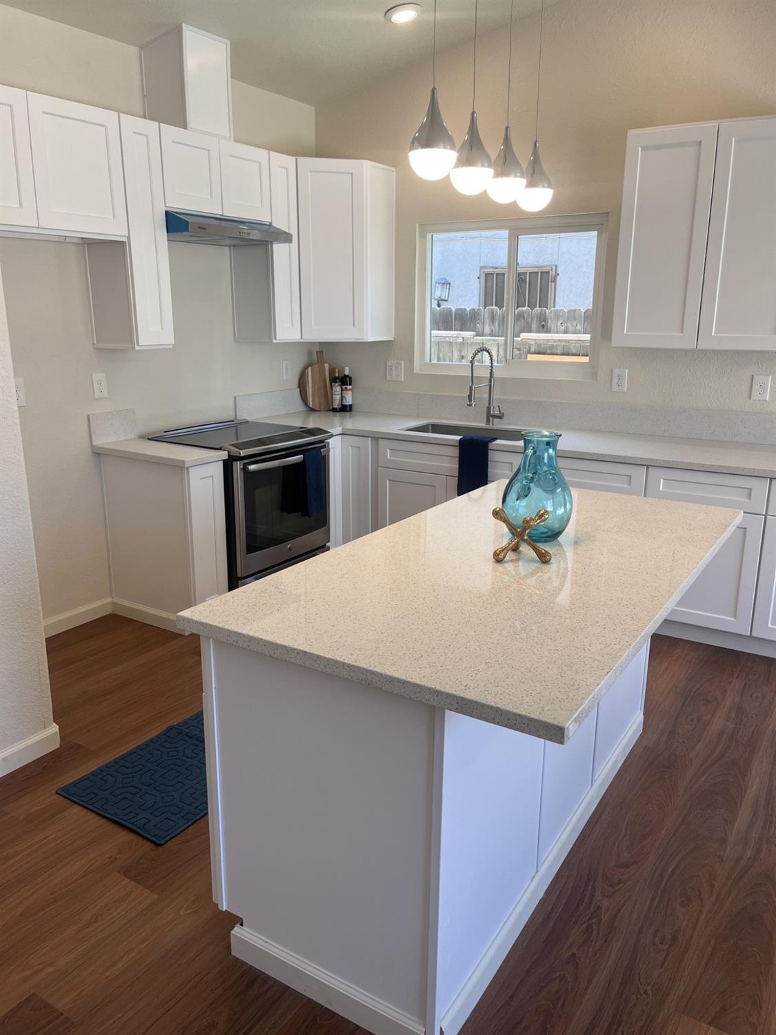 605 El Monte Street Madera, CA 93637 - Photo 4 of 17 a kitchen with kitchen island a stove a sink and a refrigerator