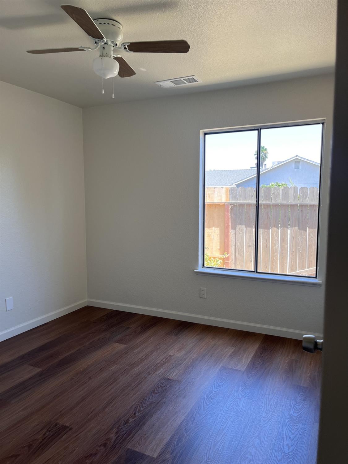 605 El Monte Street Madera, CA 93637 - Photo 9 of 17 an empty room with wooden floor and windows