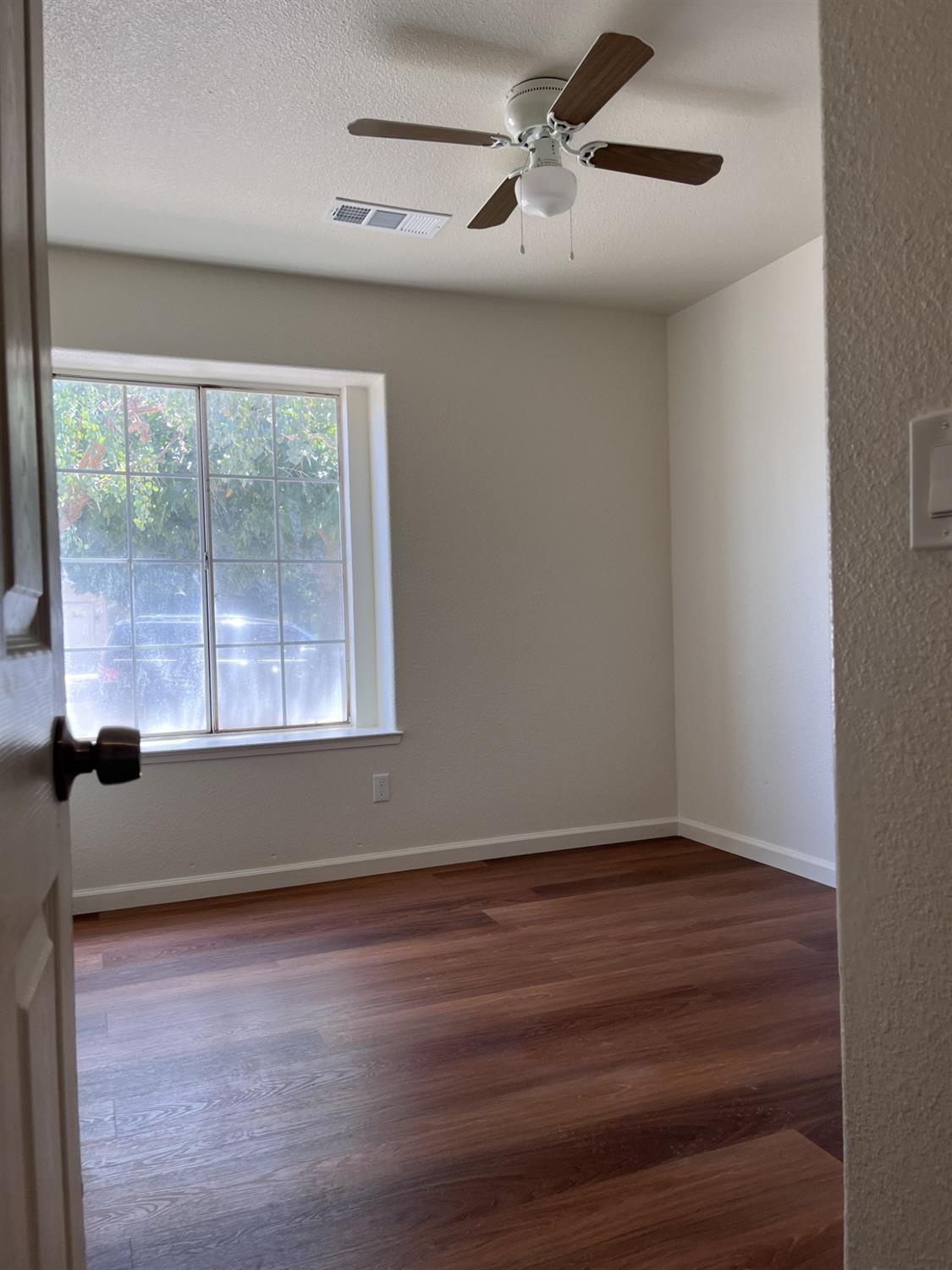 605 El Monte Street Madera, CA 93637 - Photo 10 of 17 a view of an empty room with wooden floor and a window