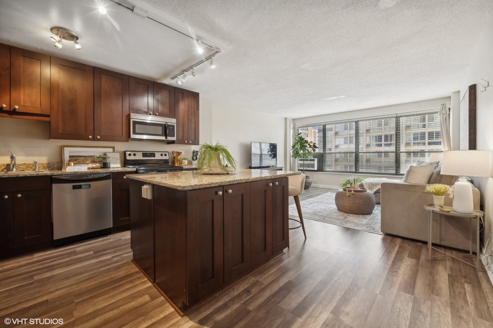 2930 North Sheridan Road, Unit 909 Chicago, IL 60657 - Photo 2 of 17 a kitchen with kitchen island granite countertop wooden floors and a view of living room