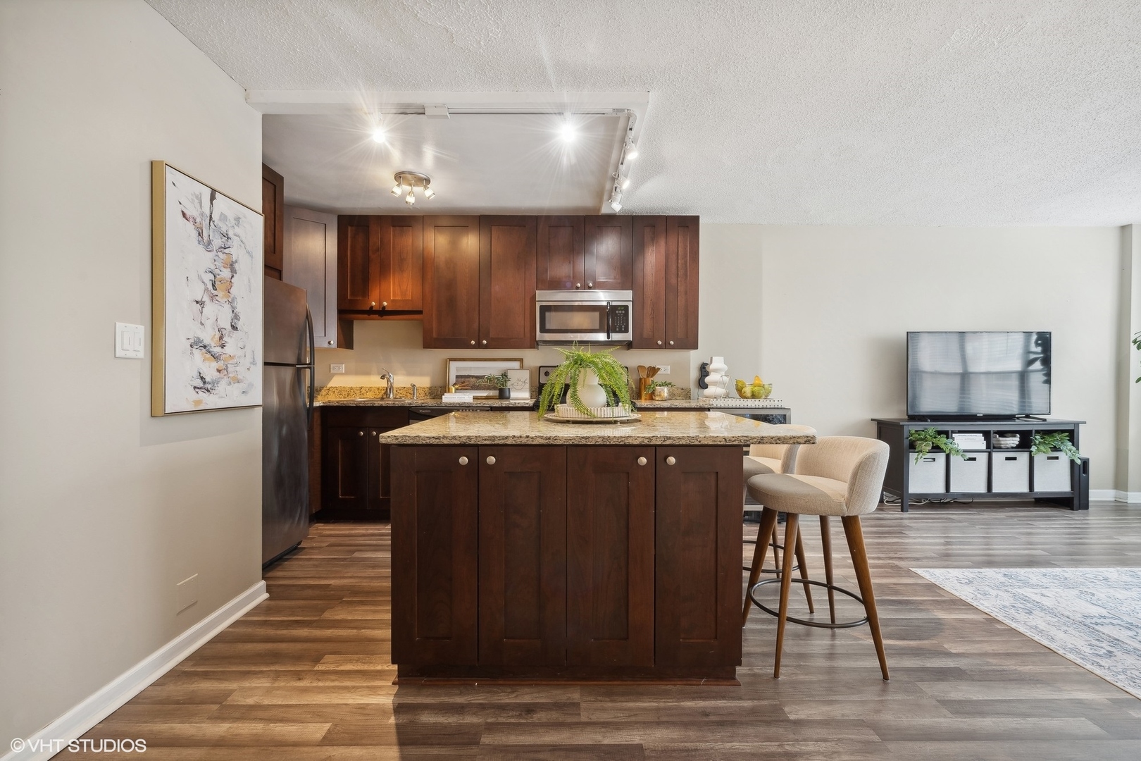 2930 North Sheridan Road, Unit 909 Chicago, IL 60657 - Photo 3 of 17 a kitchen with stainless steel appliances granite countertop a table chairs and a refrigerator