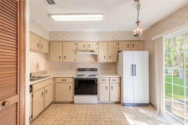 a kitchen with stainless steel appliances granite countertop a refrigerator a sink dishwasher a stove with white cabinets and wooden floor