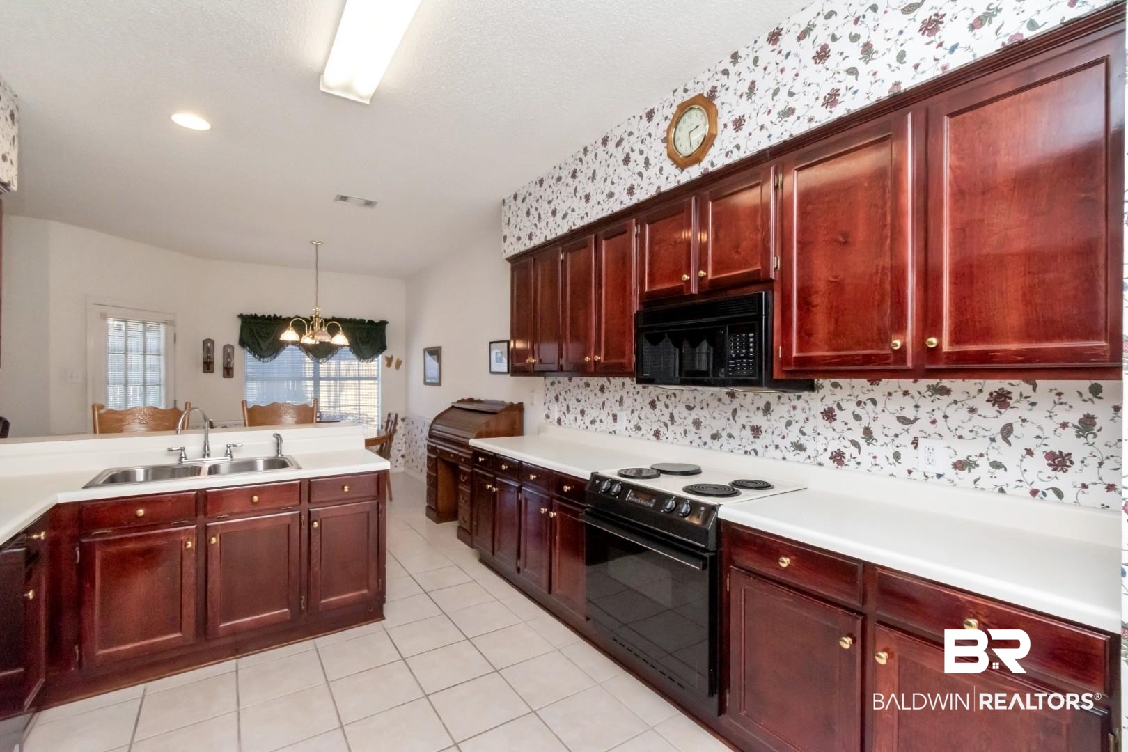 1032 Cross Gates Place Mobile, AL 36609 - Photo 15 of 34 Kitchen with hanging lights, black appliances, light countertops, reddish brown cabinets, and light tile patterned flooring